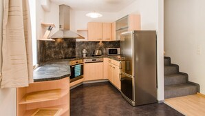 A compact kitchen with a built-in oven, microwave, and stainless steel refrigerator. - Chalet Vergissmeinnicht, spacious property in Zell am See, includes Summer Card (Zell am See)