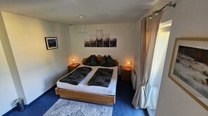 A bedroom with a bed, bedside lamps, a radiator, a rug, and a framed picture on the wall. - Chalet Vergissmeinnicht, spacious property in Zell am See, includes Summer Card (Zell am See)