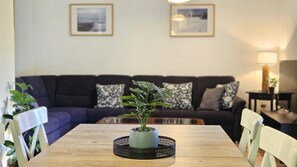 A living room with a dark-colored sofa, a wooden coffee table, and a potted plant in the center. - Chalet Vergissmeinnicht, spacious property in Zell am See, includes Summer Card (Zell am See)