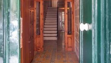 A wooden staircase leading to a room with a patterned floor and a sign that reads "Santo Antonia Court."