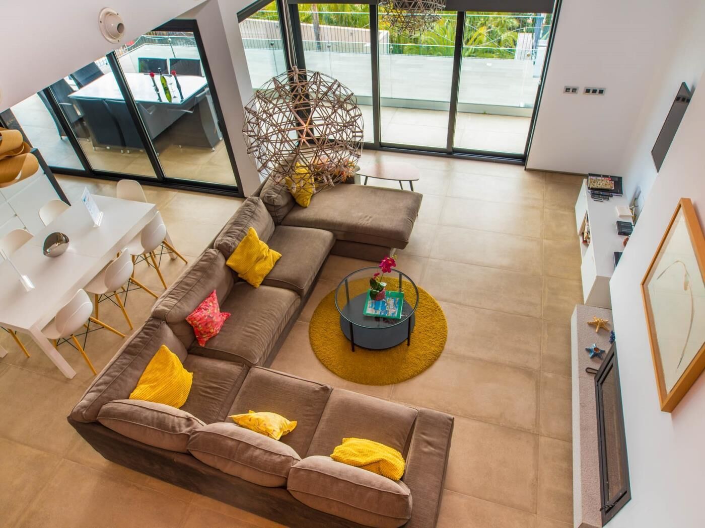 A modern living room with a sectional sofa, a dining table, and a large window offering a view of the outdoors.