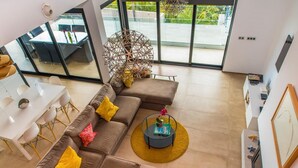 A modern living room with a sectional sofa, a dining table, and a large window offering a view of the outdoors. - Luxury villa with heated pool and sea views (Salobreña)