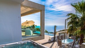 A hot tub with a view of the ocean, outdoor seating, and a covered patio area. - Luxury villa with heated pool and sea views (Salobreña)