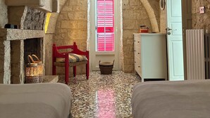 A rustic room with a stone ceiling, a red chair, a white cabinet, and a bed with a patterned rug. - Beautiful Trullo Villa with private saltwater pool and large enclosed garden (Locorotondo)