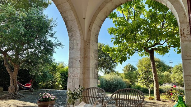 A patio with a table, two wicker chairs, and a hammock. - Beautiful Trullo Villa with private saltwater pool and large enclosed garden (Locorotondo)