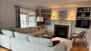A living room with a sofa, a fireplace, bookshelves, and a television. - Dates opened for Fall! new discounted rates for September. (Stowe)