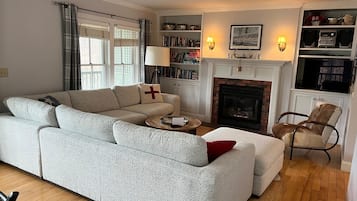Een woonkamer met een bank, een open haard, boekenkasten en een televisie.