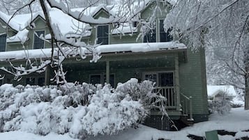 A snow-covered house with a small porch and a green door.