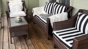A cozy porch with wicker furniture, a glass table, and a window with a lamp. - Dates opened for Fall! new discounted rates for September. (Stowe)