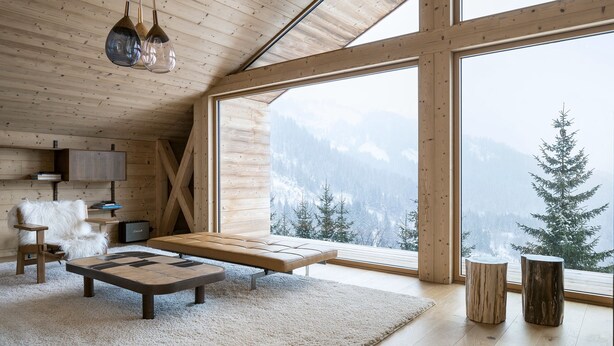 A spacious room with a high ceiling, wooden beams, a large window with a mountain view, a sofa, a coffee table, and a fireplace. - Barma Chalet - Luxurious modern chalet, exceptional view, 900 m from the slopes (Manigod)