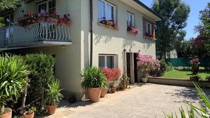 A two-story house with a balcony, potted plants, and a well-maintained garden.