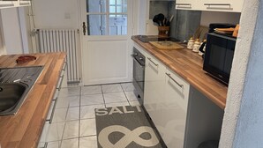 A modern kitchen with white cabinets, a wooden countertop, a sink, a stove, and a microwave.