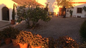 A courtyard with cobblestone flooring, a white building with a tiled roof, and potted plants. - 2 Bedroom, Fully Air-conditioned Country House With Large Private Pool (santa barbara de nexe)
