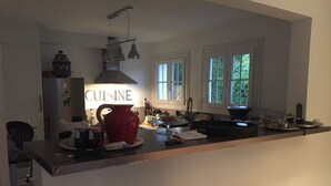 Uma cozinha com uma bancada comprida, uma panela vermelha e uma placa com a palavra 'CUISINE'.
