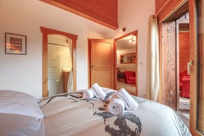 A bedroom with a bed, two doors, and a red chair. - Apartment Apollo 7p/3r (Les Houches)