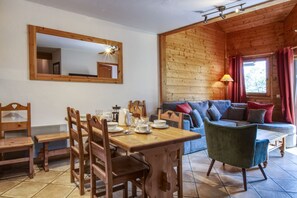 Un interno in legno con un tavolo da pranzo, sedie, un divano e una finestra con tende.