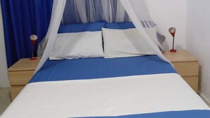 A bed with a blue and white bedspread, a white canopy, and blue curtains.