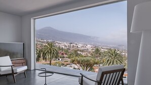 Un salon moderne doté d’une grande fenêtre, d’un téléviseur à écran plat, d’une table ronde et de deux chaises.