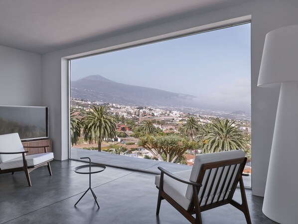 A modern living room with a large window, a flat-screen TV, a round table, and two chairs. - Your "Boutique" Home with views!! (La Orotava)