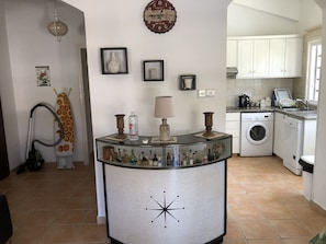 A kitchen with a washing machine, a sink, and a countertop with various items. -  Villa Lamda A Beautiful Modern Bungalow in Tranquil Peaceful Pissouri Village. (Pissouri)