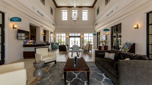 A spacious lobby with a central coffee table, seating area, and a reception desk.