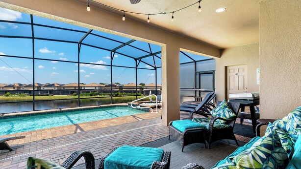 A poolside area with wicker furniture and a view of a water body.
