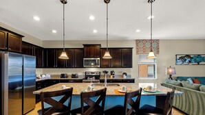 A modern kitchen with dark wood cabinets, stainless steel appliances, and a central island with bar stools.
