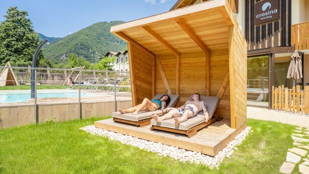 A wooden structure with two lounge areas, a pool, and a mountainous backdrop. - Residence Toli Pool with outdoor heated Pool 30° (Ledro)