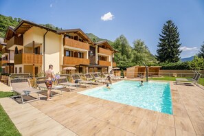 Ett hotell med en swimmingpool, solstolar och en imponerande bergskedja i bakgrunden.