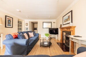 A living room with a blue sofa, a glass coffee table, a fireplace, and a TV.