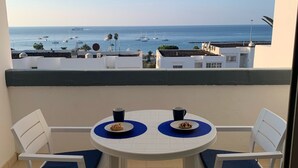A balcony with a white table and chairs, two plates with pastries, and a view of the sea with boats. - Modern1 bed apt. full seaview. Beside Golden Mile (Los cristianos)