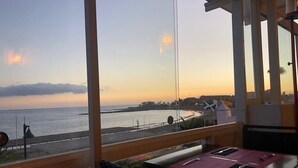 A balcony with a view of the sea at sunset, a table with a chair, and a flag. - Modern1 bed apt. full seaview. Beside Golden Mile (Los cristianos)