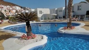 A swimming pool with palm trees and a white building in the background. - Modern1 bed apt. full seaview. Beside Golden Mile (Los cristianos)