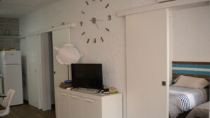Ein Schlafzimmer mit einem Bett, einem Fernseher auf einer Kommode und einer Uhr an der Wand.
