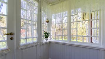 Une pièce aux murs recouverts de lambris blancs et dotée de grandes fenêtres ornées de rideaux en dentelle.