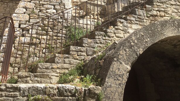A stone building with a staircase leading up to a door, surrounded by other stone structures.