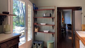 A kitchen with wooden shelves, a window, and a door leading to a bathroom.