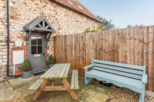 A stone building with a wooden door, a picnic table, and a bench. - Hideaway Barn, Thornham, Norfolk (Thornham)