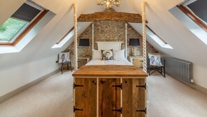 A bedroom with a wooden four-poster bed, a stone wall, and skylights. - Hideaway Barn, Thornham, Norfolk (Thornham)