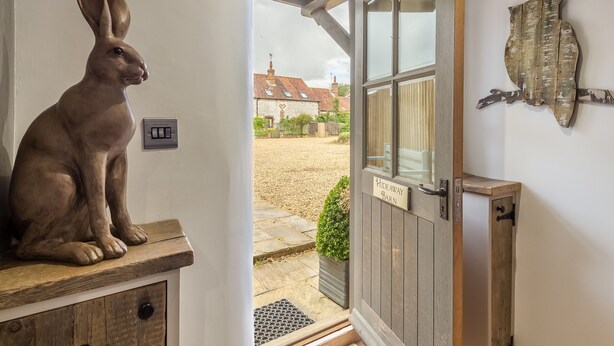 A rustic wooden door with a sign reading "Hideaway Barn" leading to a courtyard with a stone path and a small garden. - Hideaway Barn, Thornham, Norfolk (Thornham)
