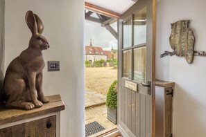 A rustic wooden door with a sign reading "Hideaway Barn" leading to a courtyard with a stone path and a small garden. - Hideaway Barn, Thornham, Norfolk (Thornham)