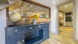 A dark blue wooden console table with a globe and a vase of sunflowers. - Hideaway Barn, Thornham, Norfolk (Thornham)