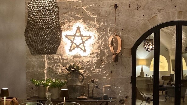 A rustic dining area with a stone wall, a wooden table, and a Star of David decoration.