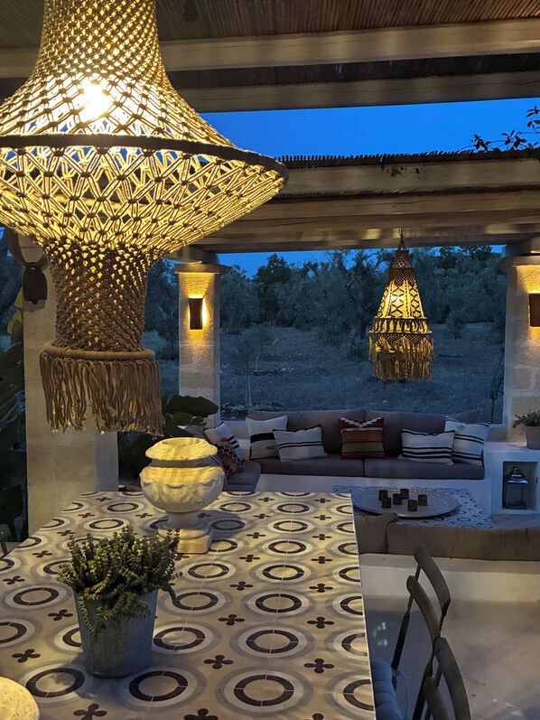 An outdoor seating area with a patterned table, a hanging lamp, and a wall-mounted lamp.