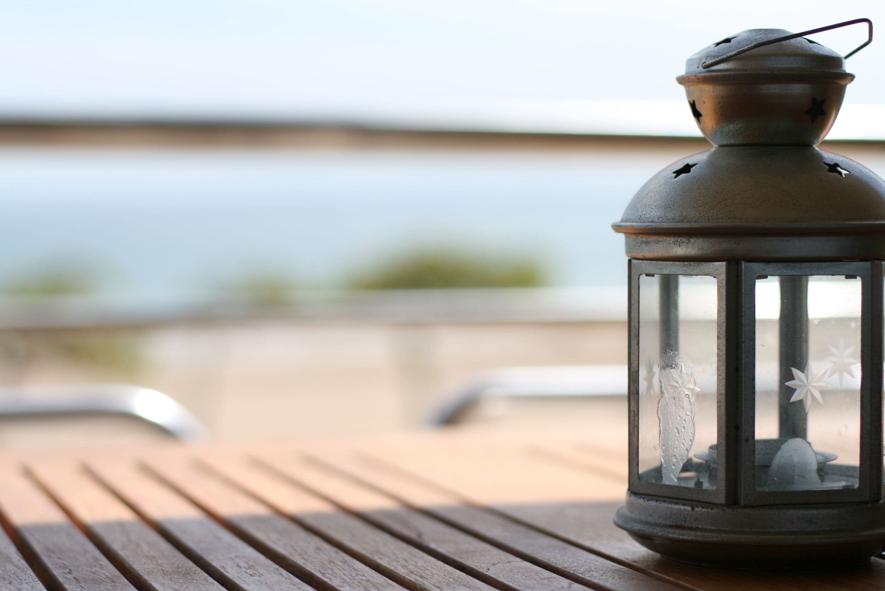 A lantern on a wooden deck with a view of the sea.