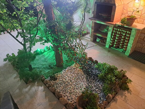 A landscaped indoor area with a stone fireplace, a small tree, and a pebbled area.