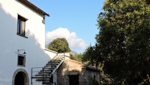 A building with a staircase leading to a stone structure, a small window, and a chair outside.
