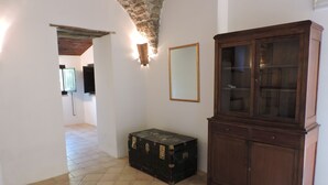 A room with a tiled floor, a wooden cabinet, a wall-mounted light fixture, and a framed mirror.