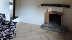 A room with a fireplace, a window, and a patterned sofa.
