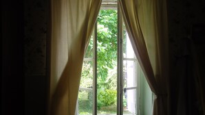 Une pièce dotée d’une grande fenêtre, de rideaux et offrant une vue sur la verdure environnante.